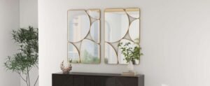 Modern wall decor featuring four gold-framed geometric mirrors above a dark console with greenery.