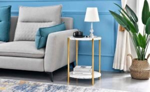 Modern blue living room with gray sofa, gold side table, lamp, and indoor plant.